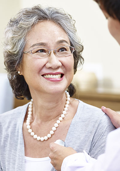 Senior woman smiling as nurse captures heartbeat